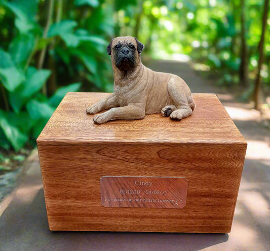 Wooden urn with a dog figurine on top, placed on a wooden surface.
