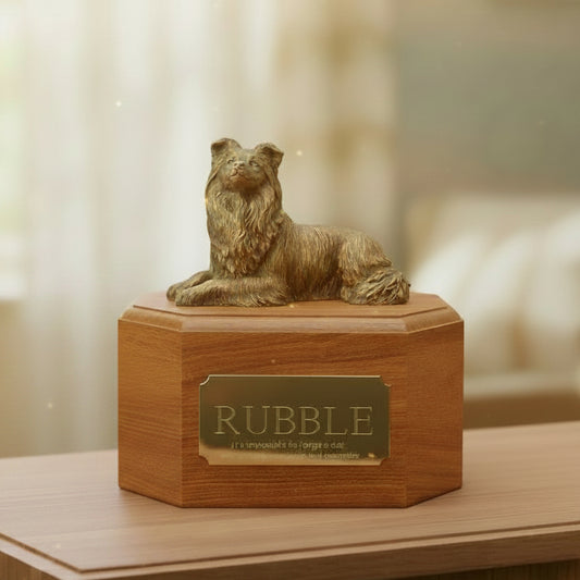 Wooden urn with a bronze dog figurine on top, placed on a wooden surface.
