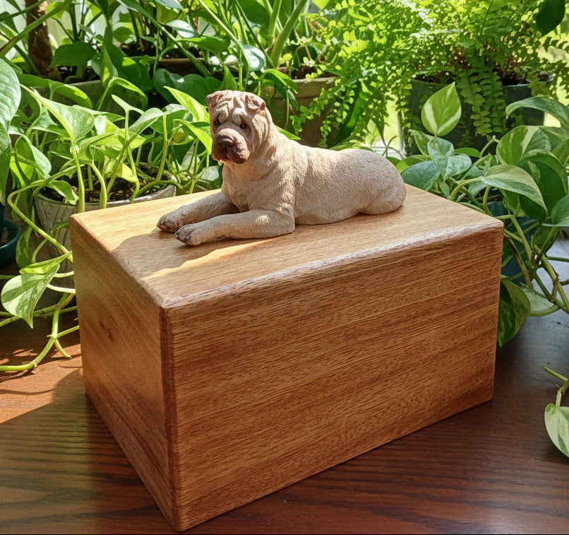 Wooden urn with a sharpei dog figurine on top, surrounded by green plants.