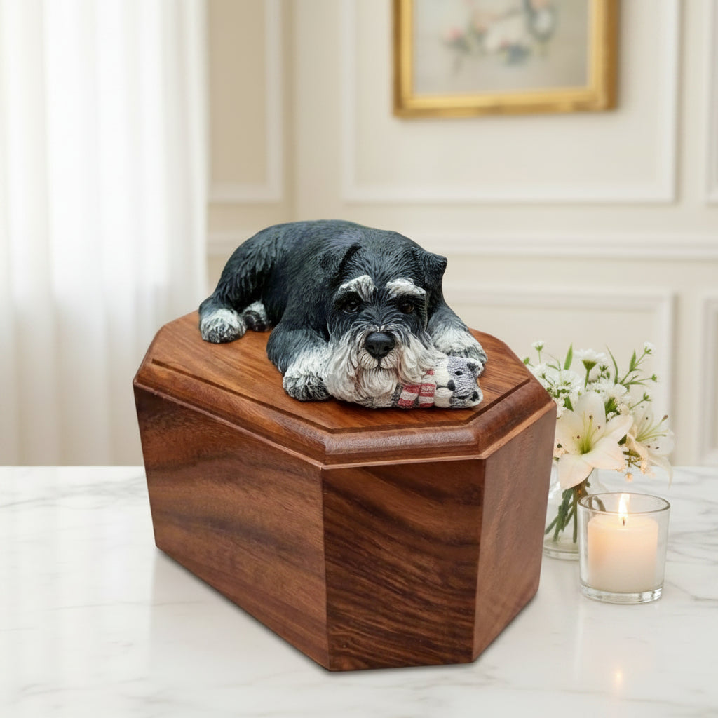 Wooden pet urn with a dog figurine on top, set against a blurred green and brown background.