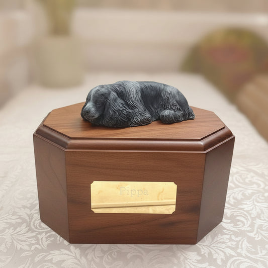 Wooden urn with a small figurine on top, placed on a bed.