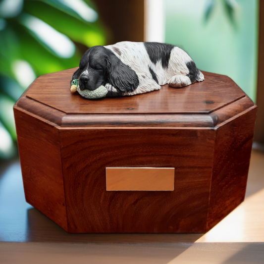 Wooden pet urn with a Springer Spaniel dog figurine on top against a blurred green background