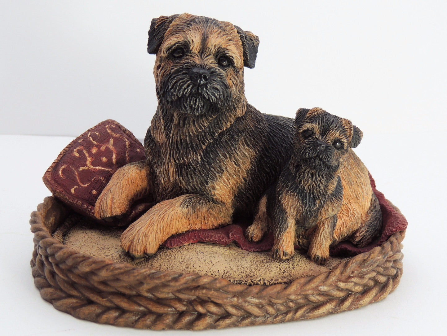 Sculpture of a red border terrier and puppy in a basket
