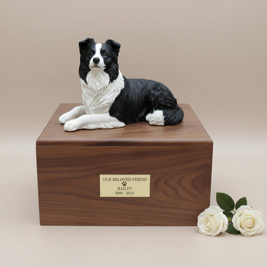 Wooden pet urn with a black and white Border Collie dog figurine on top, featuring a gold plaque.